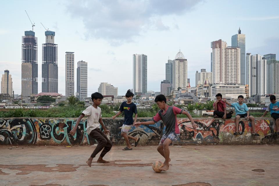 Sejumlah anak bermain bola dengan latar belakang pembangunan gedung bertingkat di Jakarta, Rabu (6/11/2024).