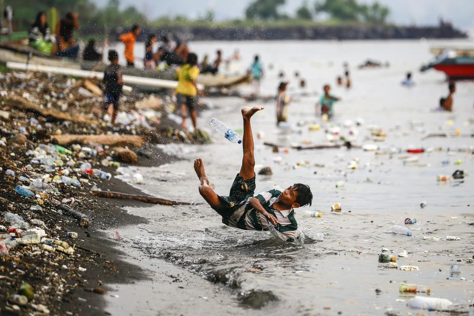 Dua orang anak bermain di pantai sambil berenang antara sampah plastik yang mengapung di laut di Pantai Kalumata Ternate, Maluku Utara, Jumat (15/11/2024).