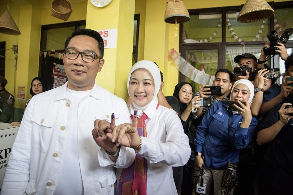 Calon gubernur (Cagub) DKI Jakarta nomor urut 1 Ridwan Kamil (kiri) bersama istri sekaligus Anggota Komisi VIII DPR RI Atalia Praratya (kedua kiri) menunjukkan tinta pada jari usai menggunakan hak pilihnya menggunakan hak pilihnya pada pilkada serentak 20