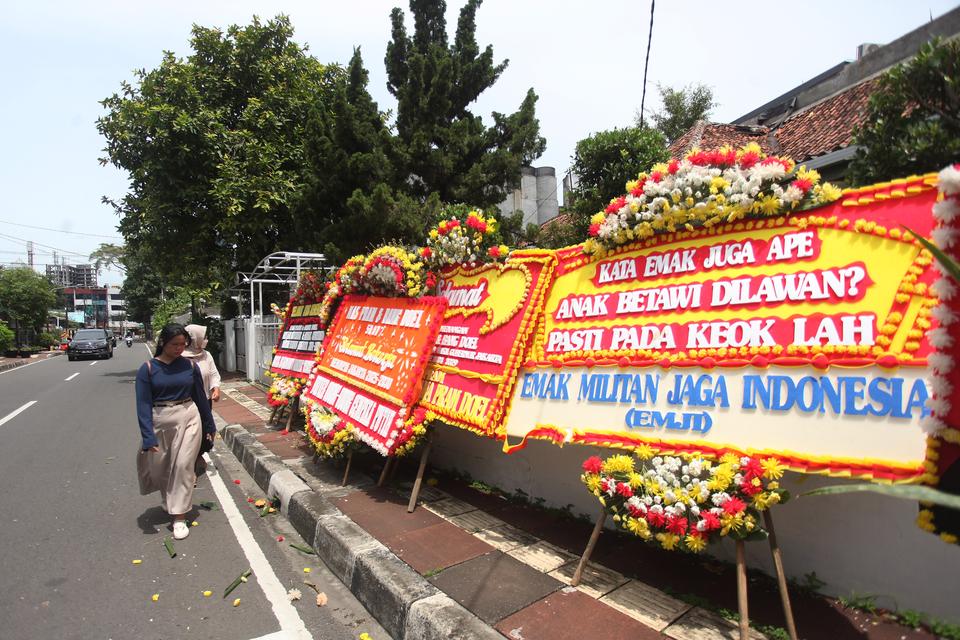 Warga melintasi karang bunga yang berjejer di sekitar Rumah Pemenangan pasangan cagub dan cawagub DKI Jakarta Pramono Anung dan Rano Karno di Jalan Cemara, Jakarta, Sabtu (30/11/2024). Karangan-karangan bunga tersebut memenuhi kawasan sekitar posko pemena