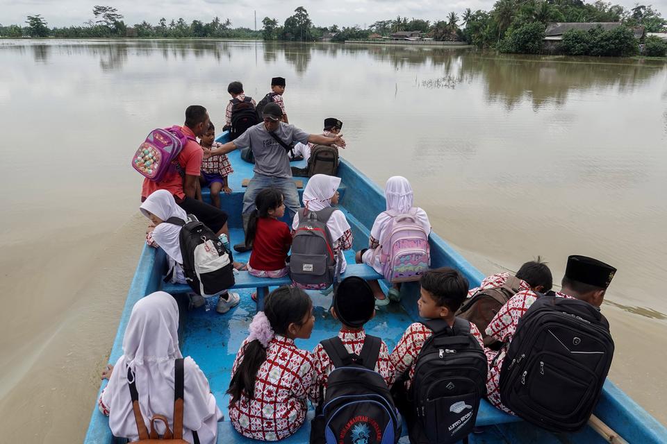 Sejumlah pelajar melewati banjir menggunakan perahu saat kembali ke rumah mereka di Desa Gentasari, Kroya, Cilacap, Jawa Tengah, Rabu (4/12/2024). 