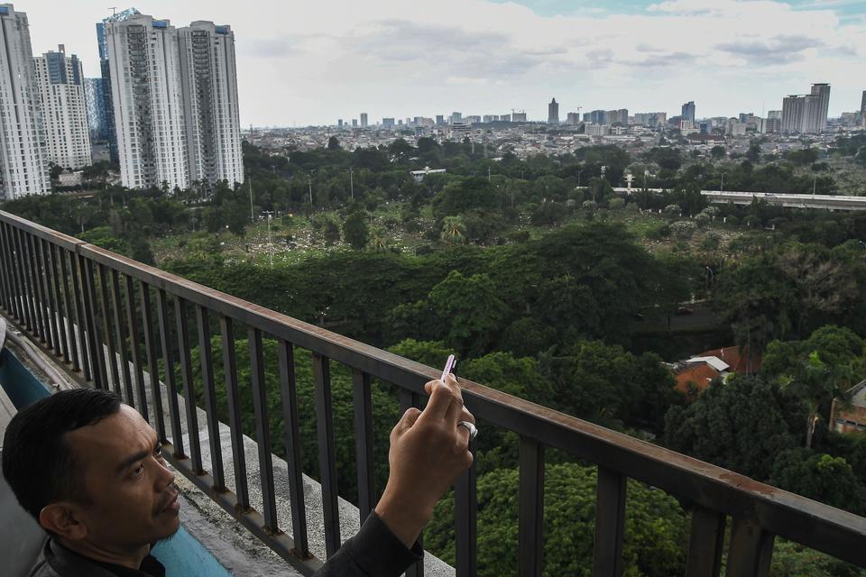 Warga memotret pepohonan dengan latar belakang gedung bertingkat di Karet Kuningan, Jakarta Selatan, Jumat (13/12/2024). Pemerintah Provinsi DKI Jakarta berkomitmen menambah RTH yang saat ini baru mencapai 5,3 persen atau seluas 34,46 juta meter persegi 