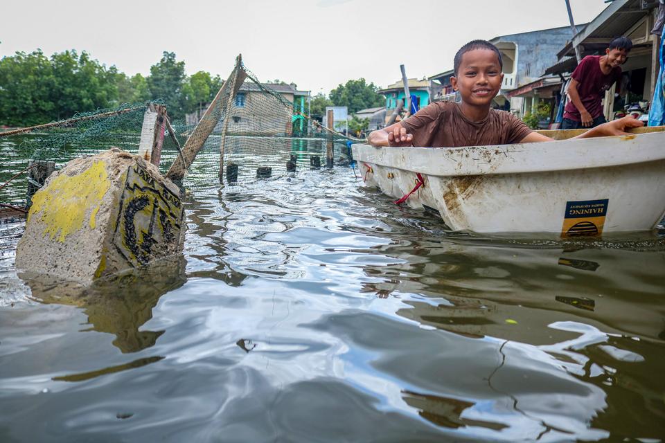 Dua anak bermain saat banjir rob di kawasan Marunda Pulo, Jakarta, Rabu (4/12/2024). 