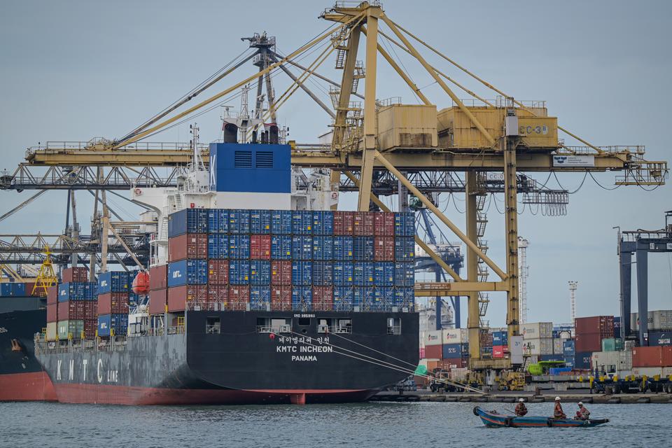 Petugas menggunakan perahu melintas dengan latar bongkar muat peti kemas di Jakarta International Container Terminal (JICT), Tanjung Priok, Jakarta, Kamis (19/12/2024). Badan Pusat Statistik melaporkan bahwa surplus neraca dagang Indonesia pada November 2