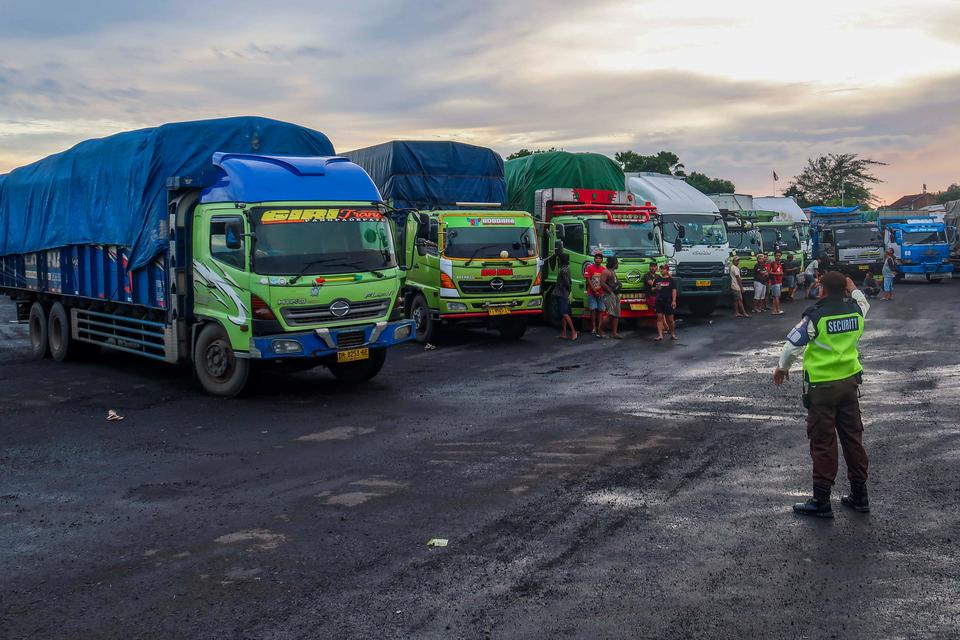 Petugas mengarahkan truk pengangkut logistik parkir di kantong parkir Dermaga Bulusan, Pelabuhan Ketapang, Banyuwangi, Jawa Timur, Minggu (22/12/2024). PT ASDP Ketapang menyiapkan 3 kantong parkir untuk kendaraan angkutan logistik yang terletak di Dermaga