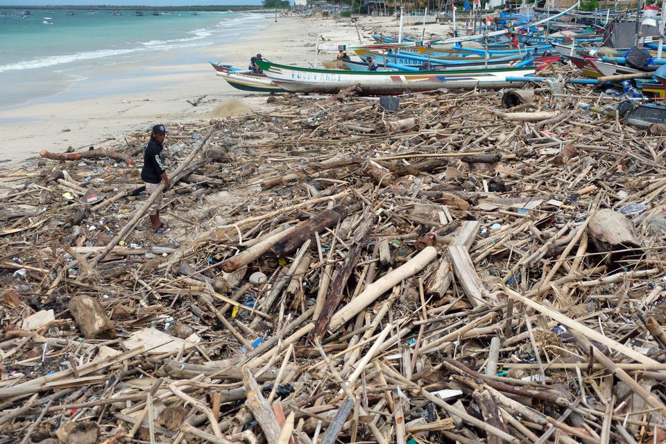 Nelayan memindahkan sampah kayu yang berserakan di kawasan Pantai Kedonganan, Badung, Bali, Jumat (27/12/2024). Sampah kiriman berupa kayu, bambu, dan plastik yang berserakan di pesisir pantai sejak awal Desember 2024 itu dikeluhkan nelayan karena menyeba