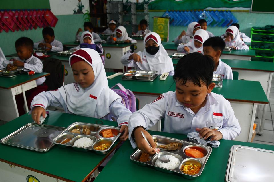 Sejumlah murid menikmati paket makan program Makan Bergizi Gratis (MBG) untuk dibagikan di kelasnya pada hari pertama di MI Islamiyah, Kota Madiun, Jawa Timur, Senin (6/1/2025). 