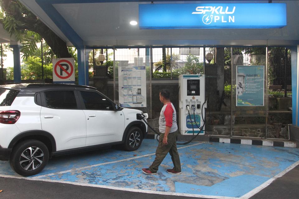 Warga melintas di depan Stasiun Pengisian Kendaraan Listrik Umum (SPKLU) di halaman PLN UP3 Malang, Jawa Timur, Kamis (16/1/2025). Pemerintah berupaya membentuk ekosistem kendaraan listrik dengan menambah 31.859 unit SPKLU di seluruh Indonesia untuk memen