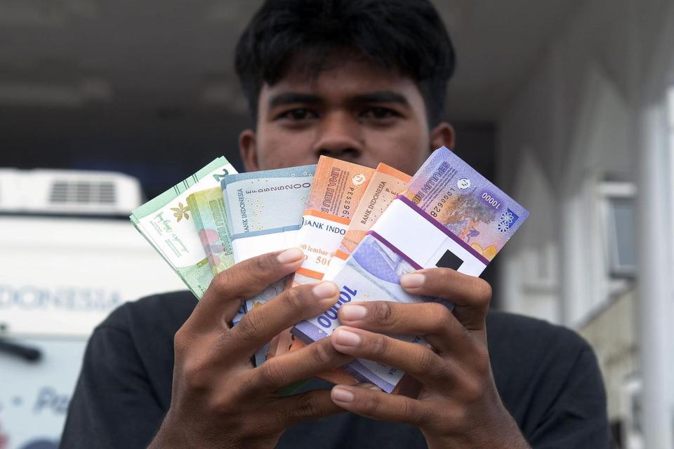 Warga menunjukkan uang pecahan baru saat layanan penukaran uang dari mobil kas keliling Bank Indonesia di Masjid Al-Furqon, Bandar Lampung, Lampung, Selasa (4/3/2025).=