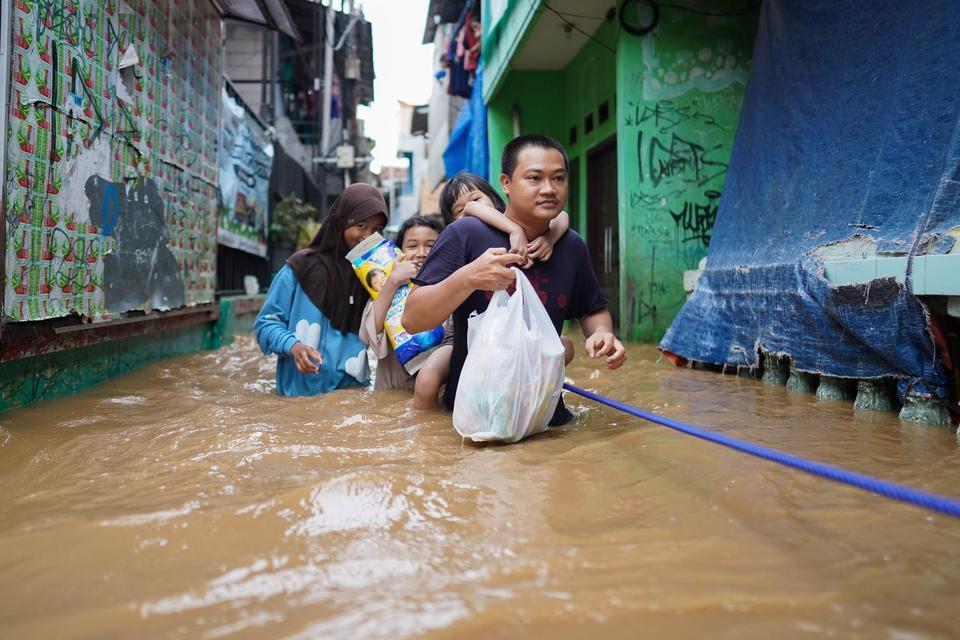 Sejumlah warga melintasi banjir di Kebon Pala, Jakarta, Selasa (4/3/2025). Badan Meteorologi, Klimatologi, dan Geofisika (BMKG) menyatakan banjir yang merendam kawasan di Jakarta, Depok, Tangerang, dan Bekasi merupakan akibat dari hujan deras yang mengguy