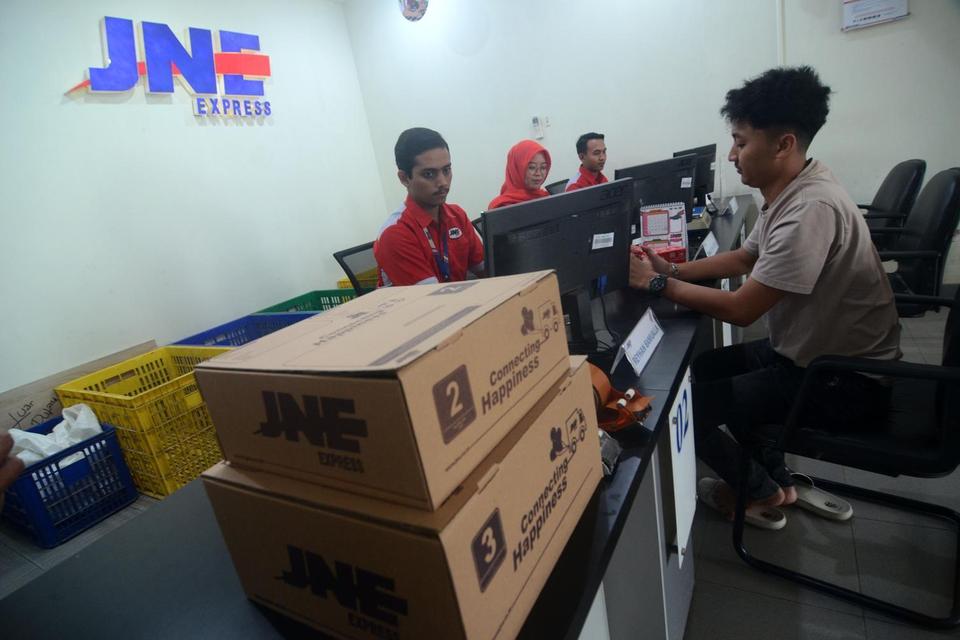 Petugas melakukan transaksi pengiriman paket di Kantor JNE Kota Tegal, Jawa Tengah, Selasa (18/3/2025).
