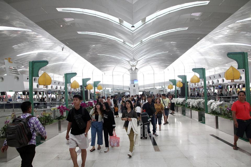 Pemudik berjalan menuju ruang keberangkatan pesawat di Bandara Internasional Kualanamu, Kabupaten Deli Serdang, Sumatera Utara, Jumat (4/4/2025).