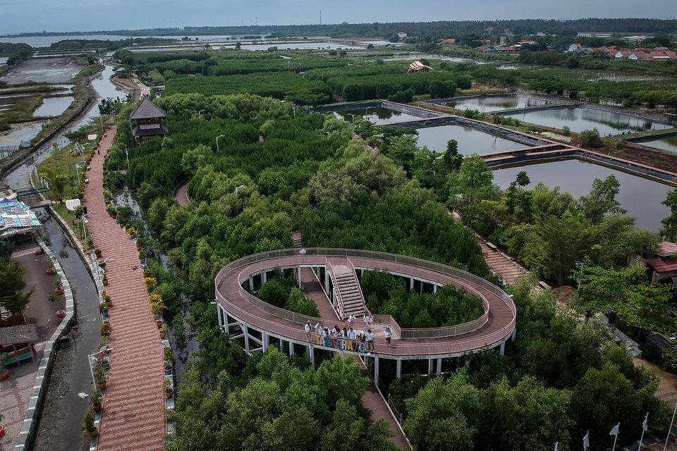 Foto udara pengunjung melintasi jembatan saat berwisata di Ketapang Urban Aquaculture, Kabupaten Tangerang, Banten, Senin (12/5/2025). 