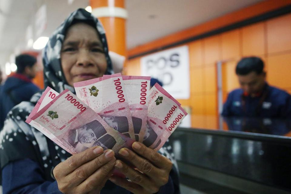 Warga menunjukan uang bantuan yang diterimanya saat penyaluran Bantuan Subsidi Upah (BSU) 2025 di Kantor Pos Indonesia Tangerang, Tangerang, Banten, Rabu (16/7/2025). Menurut Kementerian Ketenagakerjaan hingga 15 Juli 2025, Pemerintah telah menyalurkan ba
