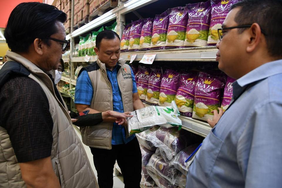 Petugas Satgas Pangan Polri memeriksa beras premium kemasan saat sidak beras oplosan di Lotte Mart, Kota Bogor, Jawa Barat, Selasa (22/7/2025).