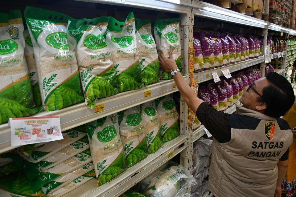 Petugas Satgas Pangan Polri memeriksa beras premium kemasan saat sidak beras oplosan di Lotte Mart, Kota Bogor, Jawa Barat, Selasa (22/7/2025). Sidak yang dilakukan Satgas Pangan Polri bersama Bapanas dan Dinas Koperasi, UKM, Perdagangan dan Perindustrian