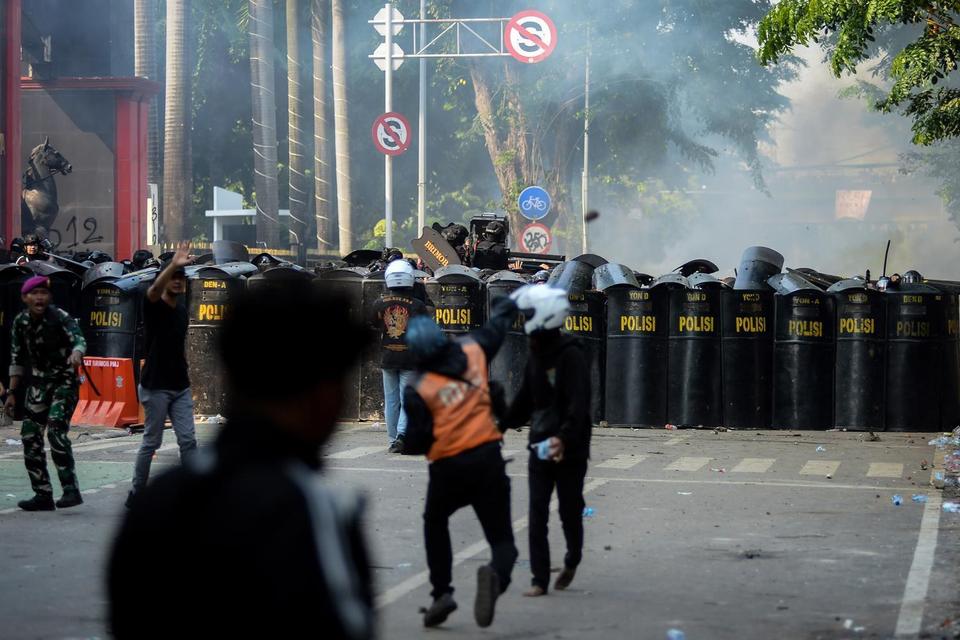 Personel Brimob memasang prisai saat adanya lemparan batu dari pengunjuk rasa dalam aksi menuntut pengusutan kasus penabrakan pengemudi ojek online oleh mobil rantis Brimob di depan Markas Komando Brimob Polda Metro Jaya, Kwitang, Jakarta, Jumat (29/8/202