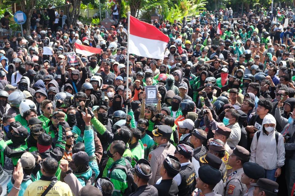 Massa dari gabungan mahasiswa dan pengemudi ojek daring menyanyikan lagu Indonesia Raya saat unjuk rasa di depan Polda Bali, Denpasar, Bali, Sabtu (30/8/2025). 