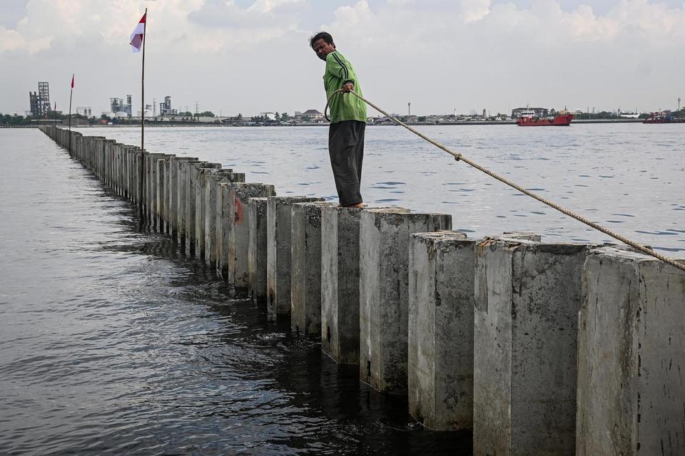 Nelayan berada di atas proyek tanggul beton di perairan Cilincing, Jakarta, Kamis (11/9/2025). Kementerian Kelautan dan Perikanan menyatakan tanggul beton tersebut bukan proyek tanggul laut melainkan proyek pengembangan terminal logistik PT Karya Citra Nu