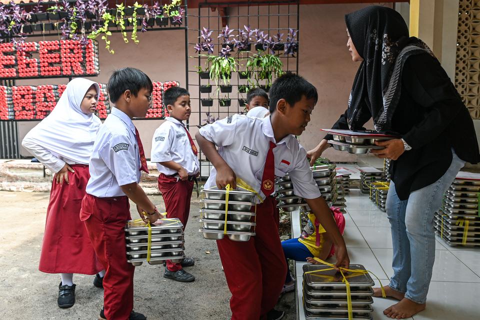 Wali murid membagikan ompreng berisi makanan kepada siswa di SDN Pejaten Barat 1 Pagi, Jakarta, Selasa (30/9/2025). 