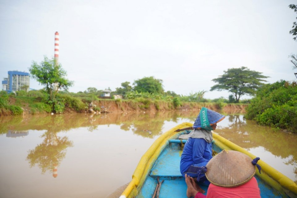 Warga setempat naik perahu melewati kawasan Pembangkit Listrik Tenaga Uap (PLTU) Cirebon-1, Jawa Barat.