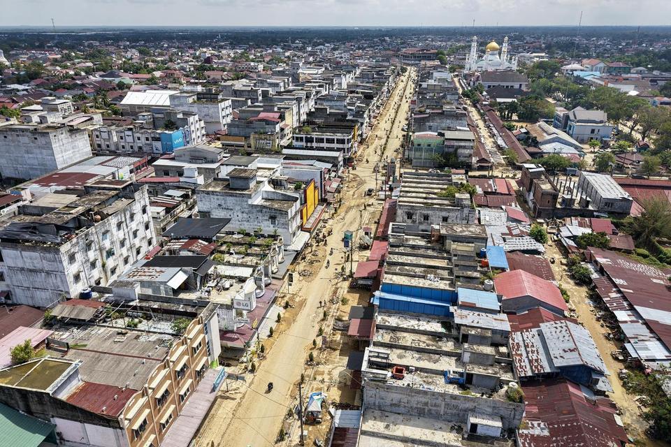 Foto udara warga dan pengendara sepeda motor melintas di jalan pascabanjir bandang di Kota Langsa, Aceh, Selasa (2/12/2025). Bencana banjir bandang yang melanda daerah tersebut pada Rabu (26/11) mengakibatkan sejumlah fasilitas umum, kantor pemerintahan, 