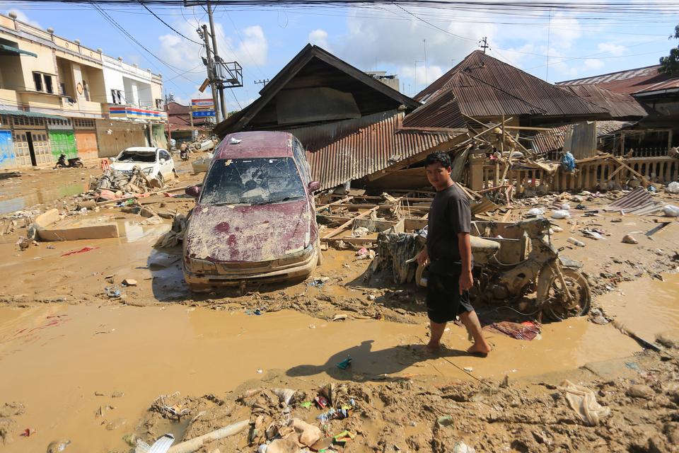 Warga melintas di dekat mobil warga yang terbawa arus banjir di kawasan Desa Bukit Tempurung, Kota Kuala Simpang, Kabupaten Aceh Tamiang, Aceh, Rabu (3/12/2025). Bencana banjir bandang yang terjadi pada Rabu (26/11) berdampak rusaknya ribuan rumah, hilan