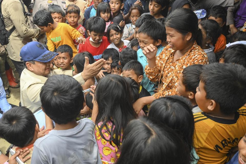 Presiden Prabowo Subianto (kiri) menyapa anak-anak saat mengunjungi posko pengungsian di Kuala Simpang, Aceh Tamiang, Aceh, Jumat (12/12/2025). Dalam kunjungannya ke lokasi posko pengungsian korban banjir bandang itu Presiden Prabowo mengatakan pemerintah