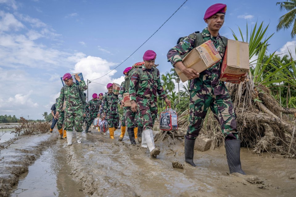 Satgas TNI AL membawa bantuan melintasi jalan berlumpur saat penyaluran bantuan untuk korban terdampak bencana alam di Desa Cot Ulaya, Kecamatan, Baktiya, Aceh Utara, Aceh. 