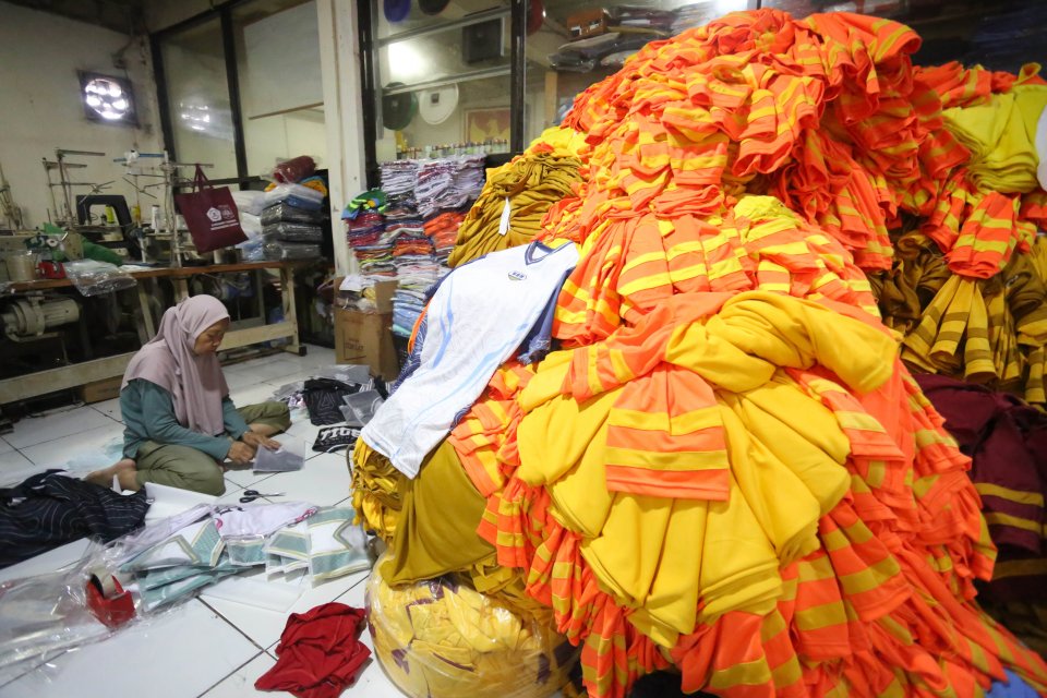 Pekerja menyelesaikan pembuatan kaos di konveksi Sinergi Adv Nusantara, Srengseng Sawah, Jakarta Selatan, Jumat (9/1/2026). Sebagai bagian dari paket stimulus ekonomi tahun anggaran 2026 Pemerintah resmi menanggung Pajak Penghasilan (PPh) Pasal 21 untuk p