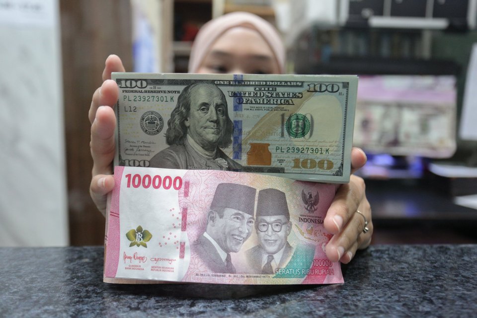 Petugas menunjukkan pecahan mata uang rupiah dan dolar Amerika Serikat (AS) di gerai penukaran uang asing di Jakarta, Rabu (21/1/2026). Nilai tukar rupiah rupiah perlahan bergerak menguat 20 poin menjadi Rp16.936 per dolar AS dari sebelumnya Rp16.956 per 