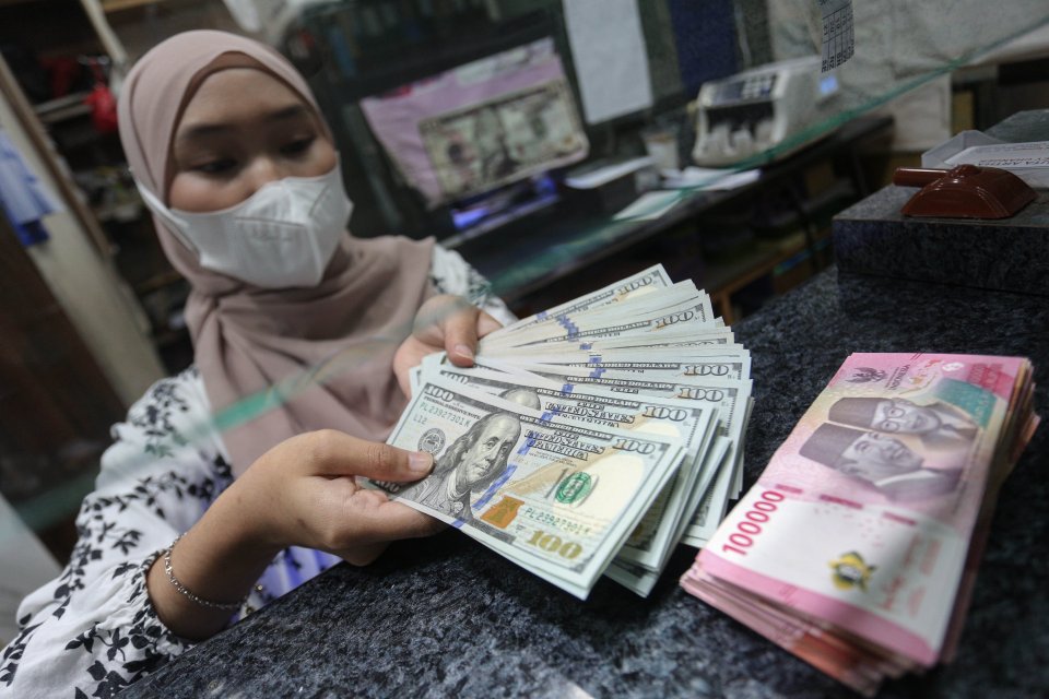 Petugas menunjukkan pecahan mata uang rupiah dan dolar Amerika Serikat (AS) di gerai penukaran uang asing di Jakarta, Rabu (21/1/2026). Nilai tukar rupiah rupiah perlahan bergerak menguat 20 poin menjadi Rp16.936 per dolar AS dari sebelumnya Rp16.956 per 