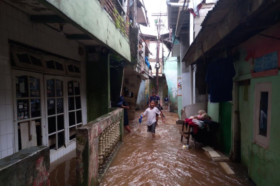 Seorang anak berjalan di tengah banjir di kawasan Kampung Melayu, Jakarta Timur, Jumat (23/1). Foto: Fauza Syahputra/Katadata