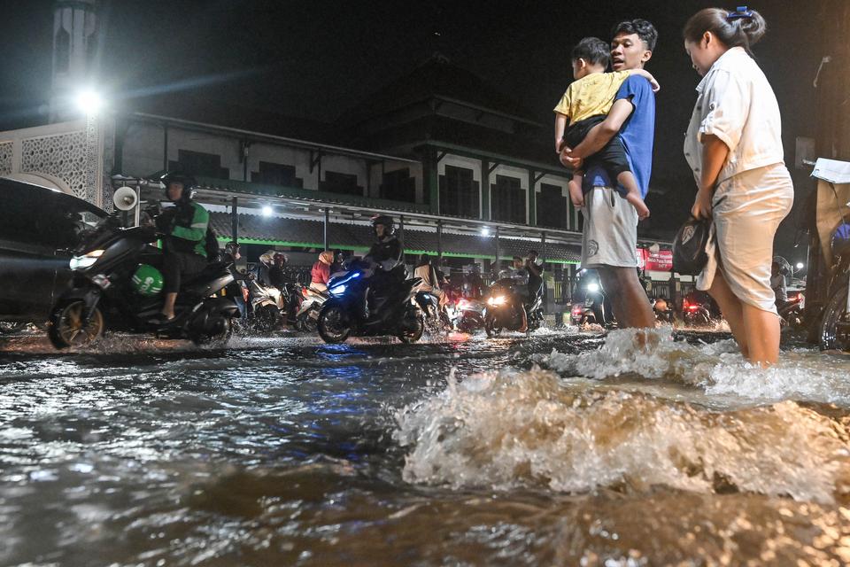 Warga menerobos banjir di Jalan Aria Putra, Ciputat, Tangerang Selatan, Banten, Sabtu (4/4/2026). 
