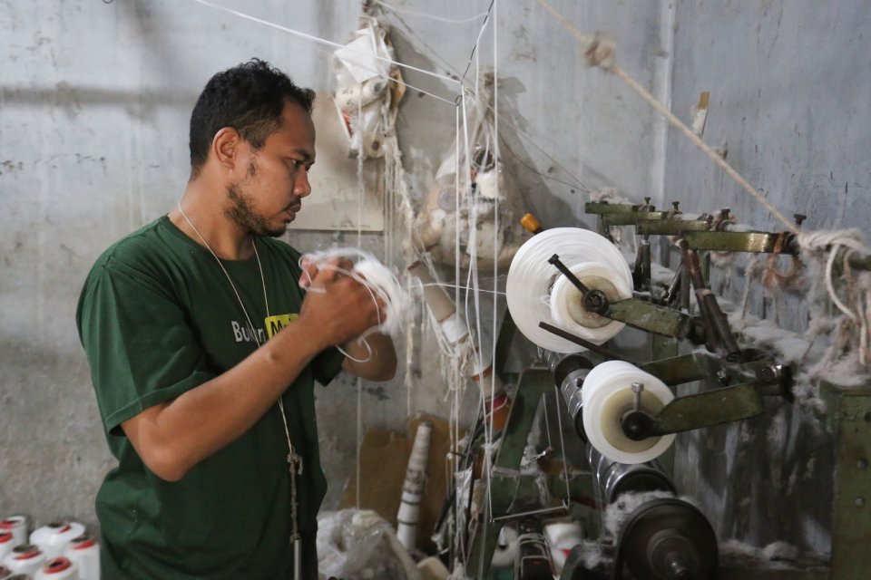 Pekerja memintal benang di Kebayoran Lama, Jakarta, Selasa (21/4/2026). Berdasarkan keterangan Saprudin (60) selaku pemilik usaha tersebut, harga bahan baku utama poliester yang melonjak berimbas pada naiknya harga benang katun dan poliester yang diproduk