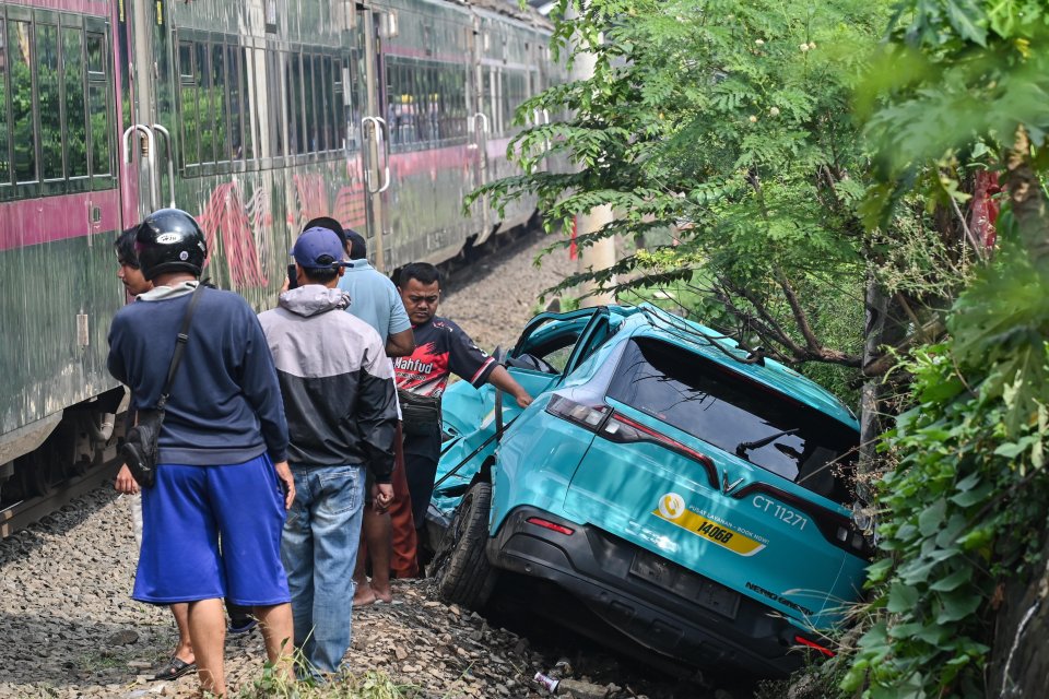 Kereta api (KA) jarak jauh melintas di samping taksi listrik Green SM yang rusak pascakecelakaan KRL Commuter Line dan KA Argo Bromo Anggrek di Stasiun Bekasi Timur, Bekasi, Jawa Barat, Selasa (28/4/2026). Komite Nasional Keselamatan Transportasi (KNKT) m