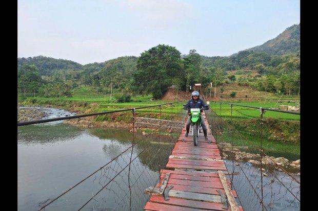 Mantri BRI Angga Sumitra mengendarai motor trail melintasi jembatan di kawasan pegunungan Garut Selatan untuk menjangkau dan melayani nasabah di pelosok Banjarwangi, Kabupaten Garut.
