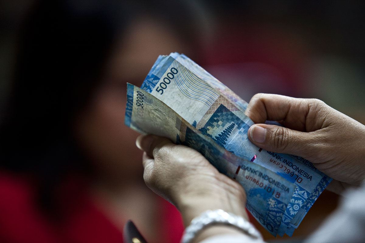 Petugas penukaran mata uang merapihkan uang yang hendak ditukar dengan mata uang asing di salah satu tempat penukaran uang di Jakarta fintech